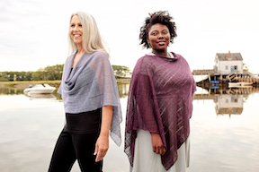Two women standing by the pier wearing linen capelets, one is lavender steel and the other is wine colored
